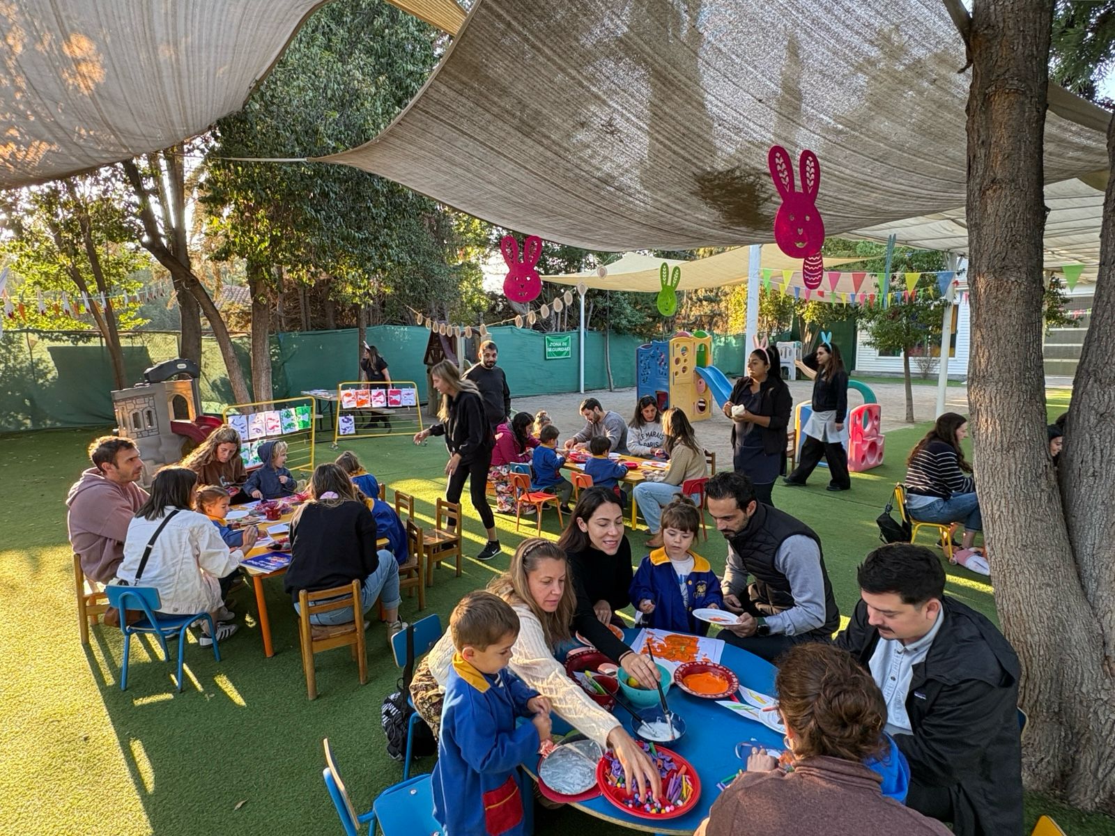 Familias compartiendo en mesas bajo toldo