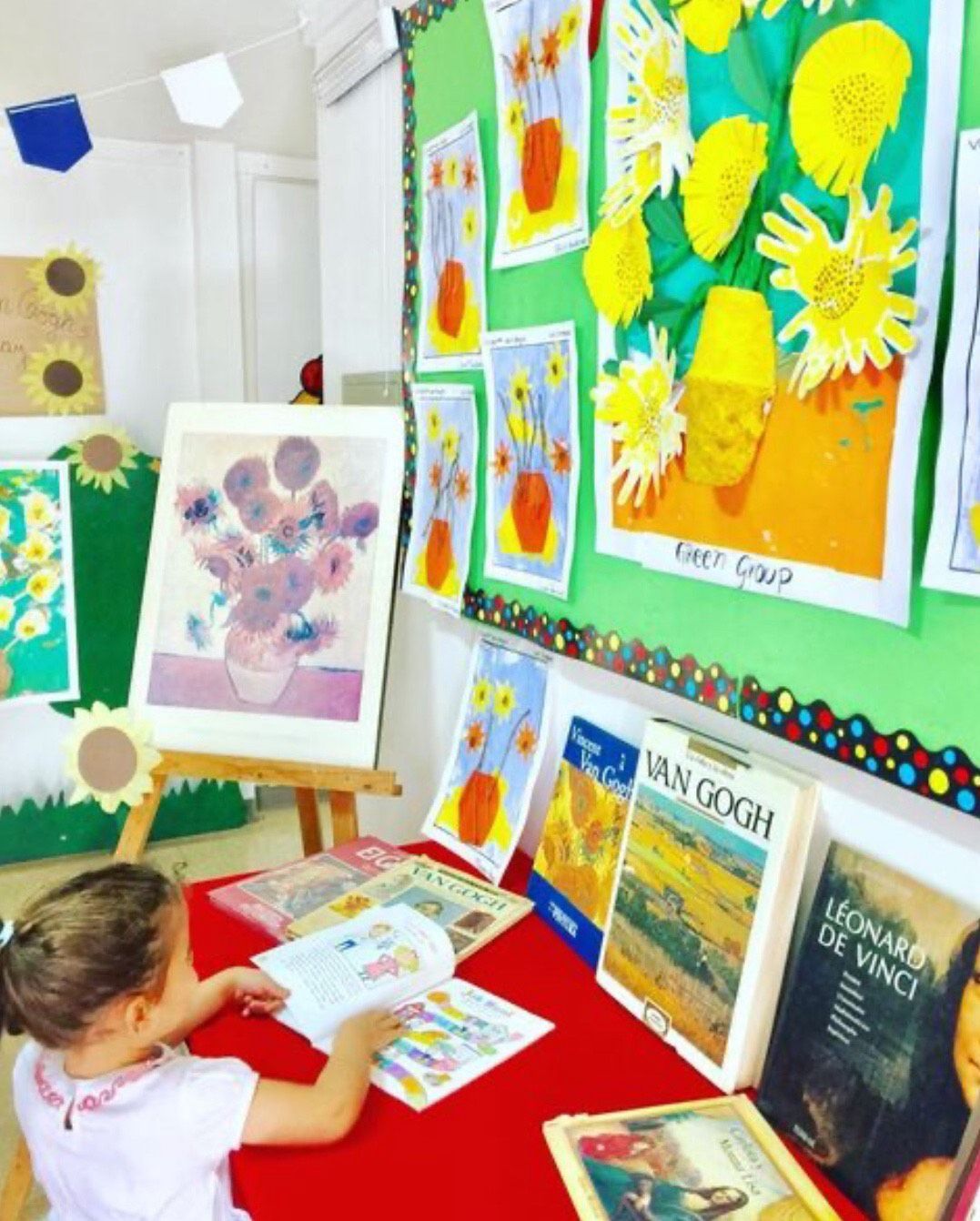 Niña leyendo libro de Van Gogh frente a mural de girasoles